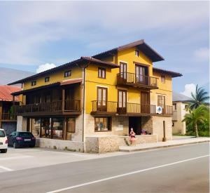 a yellow building with a woman standing in front of it at Loft el Pasaje Secreto in Solórzano