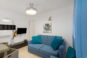 a living room with a blue couch and a tv at Casa Paula - 24 in Arinaga