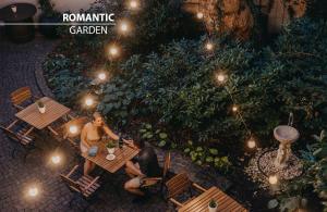people sitting at a table in a garden at night at Hotel Adler - Czech Leading Hotels in Prague +19 photos