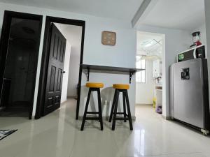 a kitchen with two bar stools and a refrigerator at Apartamento confortable y tranquilo in Manizales +3 photos