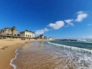 a beach with buildings and the ocean on a sunny day at Maison Albizia in Le Croisic