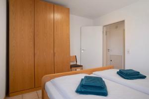 une chambre avec un lit avec deux serviettes bleues dessus dans l'établissement Gästehaus Heinemann - Og4, à Langenargen