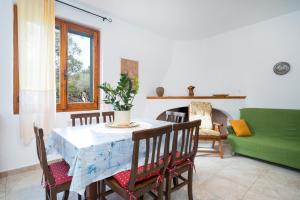 een eetkamer met een tafel en een groene bank bij Villa Francesco P Terra in Orosei