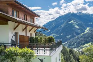 ein Haus mit einem Balkon mit Bergblick im Hintergrund in der Unterkunft Hofschenke Pfeiftal - Almenrausch in Sankt Martin in Passeier