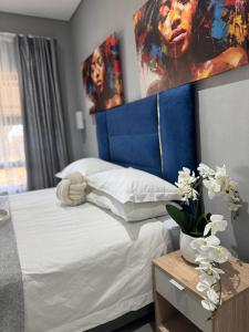 a bedroom with a bed with a blue headboard at Glow Events & Guest House in Centurion