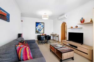 a living room with a couch and a flat screen tv at Apartamento Rossio in Albufeira