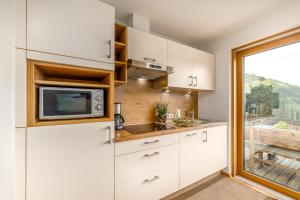 Una cocina con gabinetes blancos y un microondas. en Tratterhof Apt Eidechsspitze, en Vallarga 28 fotos más