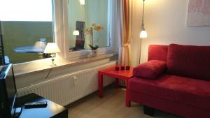 a living room with a red couch and a window at Ferienwohnung Traumblick in Hohegeiß