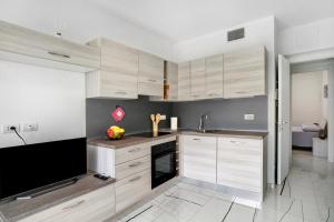 a kitchen with wooden cabinets and a flat screen tv at Le Vigne Marina di Andora in Marina dʼAndora +10 photos