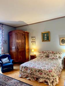 ein Schlafzimmer mit einem Bett und einem blauen Stuhl in der Unterkunft Château Le Baudou in Coutras