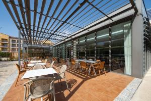 an outdoor patio with tables and chairs and windows at Zenitude Hotel La Valadière, Ascend Hotel Collection in Montpellier