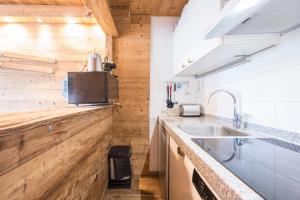 - une cuisine avec des murs en bois et un évier dans l'établissement Appartement 6p Au Pied Des Pistes, à Val Thorens 11 autres photos