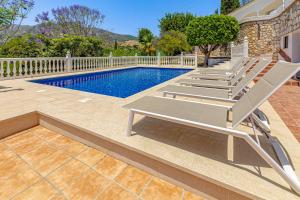 a swimming pool with benches next to a house at Luxury villa with tennis & pool in Málaga