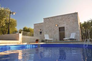 een zwembad met witte stoelen en een huis bij Lamia Pieranna in Cisternino