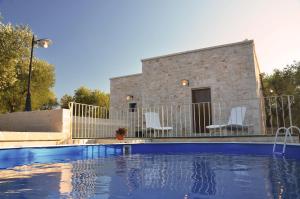 a swimming pool with white chairs and a house at Lamia Pieranna in Cisternino