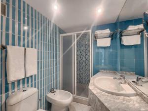 a blue tiled bathroom with a toilet and a sink at Hotel Faranda Pathos Gijón, Ascend Hotel Collection in Gijón
