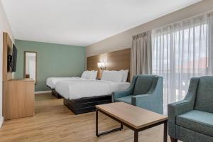 a hotel room with a bed and two chairs at MainStay Suites Springfield South - Battlefield Rd in Springfield +77 photos