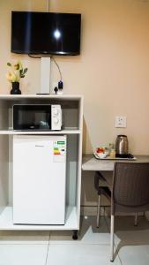 a desk with a microwave and a table with a tableablish at 3rd on Belgrave Guesthousae in Kimberley
