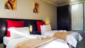 two beds in a hotel room with red pillows at 3rd on Belgrave Guesthousae in Kimberley