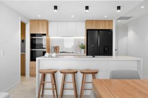 a kitchen with a large white island with bar stools at Bokarina Beach Apartments, an Ascend Collection Hotel in Bokarina