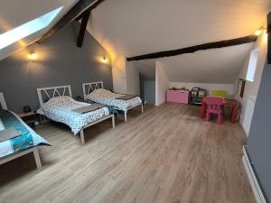 an attic room with three beds and a wooden floor at Les petits gaillards in Les Andelys