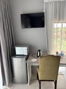 a desk with a computer and a chair next to a window at Glow Events & Guest House in Centurion