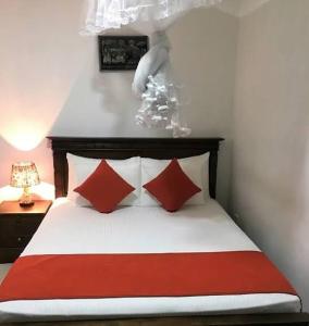 a bedroom with a bed with two red pillows at Nathaliya Home Stay For Backpackers in Negombo