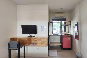 een kamer met een bureau, een televisie en een koelkast bij Samed Hotel in Ko Samed