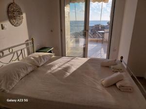 Un dormitorio con una cama grande con una ventana grande. en Menidi Sea View, en Menídion