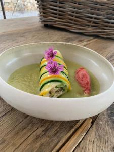 a bowl of soup with sushi with flowers on it at La Noccemada, maison d'hôtes in Saint-Julien