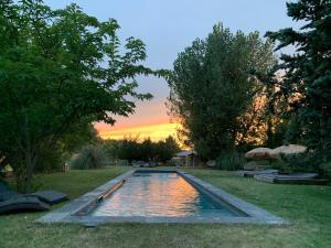 a swimming pool in a yard with a sunset in the background at La Noccemada, maison d'hôtes in Saint-Julien