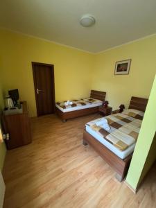 two beds in a room with yellow walls and wooden floors at Terra Wylak Winery in Veľké Zálužie +7 photos