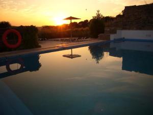 Una piscina con una puesta de sol al fondo en Brugarolas Village, en Castelltersol