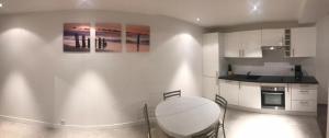 a white kitchen with a table and a counter top at Bel Appartement T2 in Annemasse