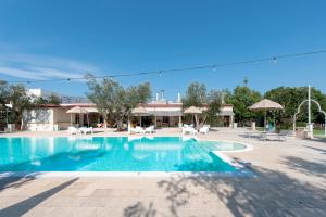a swimming pool at a resort with chairs and umbrellas at Masseria San Biagio in Calimera