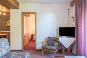 a living room with a television and a chair at Ferienparadies Sabina Schlern in Alpe di Siusi