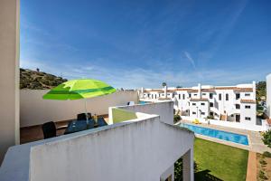 un balcone con un ombrellone verde e una piscina di Villas Brites nº5 a Burgau Altre 16 foto