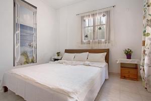 a white bedroom with a large bed and two windows at Areti Orfeas Apartment 5 in Vasilikos