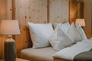 a bed with white pillows next to a wooden wall at Hof Neuhaus Sebastion in Tisens