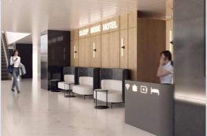 a lobby with a row of chairs and a woman walking at Sleep Mode Hotel in Shymkent