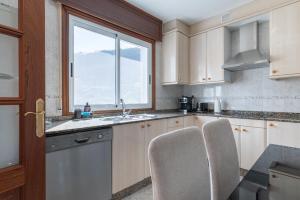 a kitchen with white cabinets and a window at Casa O Souto Cangas in Hio