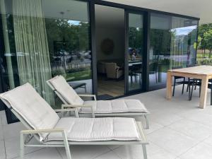 twee witte stoelen en een tafel op een patio bij Logies La Parmentière in De Panne