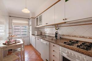a kitchen with white cabinets and a stove top oven at Mar Salgado Beach Apartment in Armação de Pêra