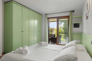 a green bedroom with a bed with towels on it at Sardegna è - Beach Rooms LE in Olbia