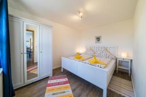 ボルクムにあるFerienwohnug Strandhaferのベッドルーム1室(黄色い枕と鏡付きのベッド1台付)