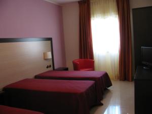 a hotel room with two beds and a red chair at Albergo Roma in San Ferdinando di Puglia