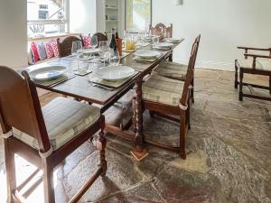 a wooden table with chairs and plates on it at Barnhay Cottage in Totnes