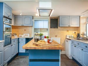 a kitchen with blue cabinets and a wooden counter top at Barnhay Cottage in Totnes +29 photos
