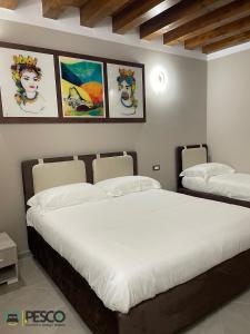 two beds in a room with paintings on the wall at Pesco Rooms Marineo in Marineo