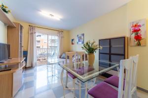 Una cocina y un comedor con una mesa de cristal y sillas. en Apartamento Esbamar Vi, en Roquetas de Mar